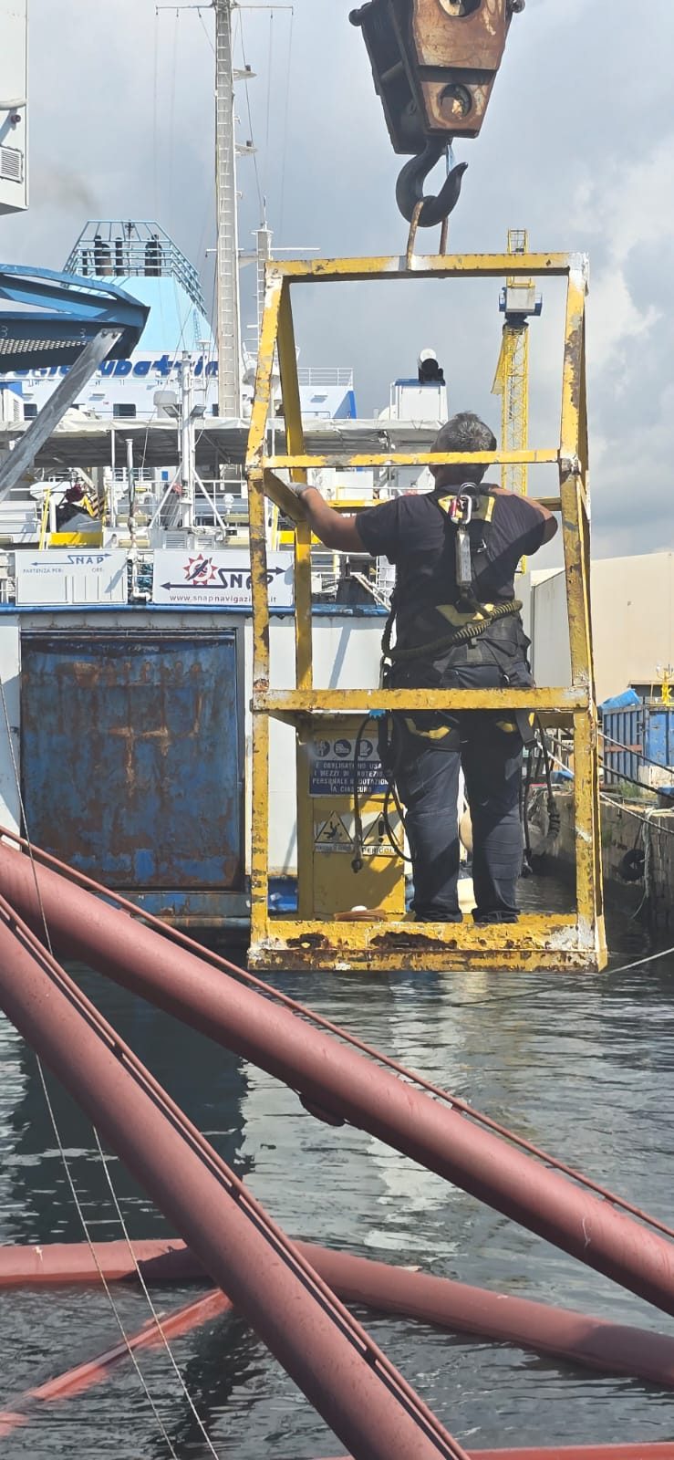 Tecnico su cestello sospeso da gru durante l'intervento in porto