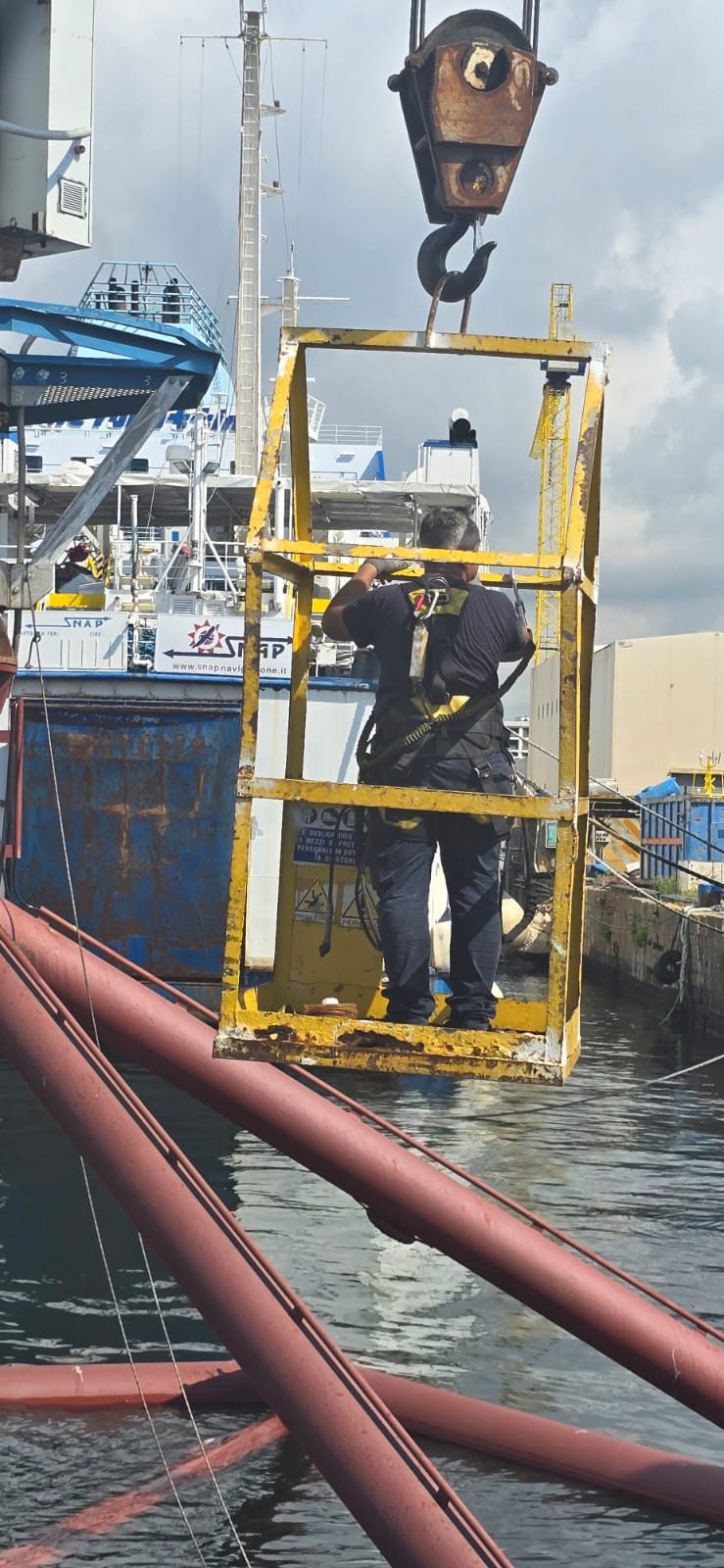 Tecnico al lavoro sul cestello sospeso sopra la base galleggiante