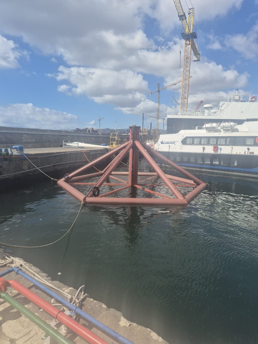 Sollevamento turbina minieolica galleggiante in porto, gru e tecnici al lavoro